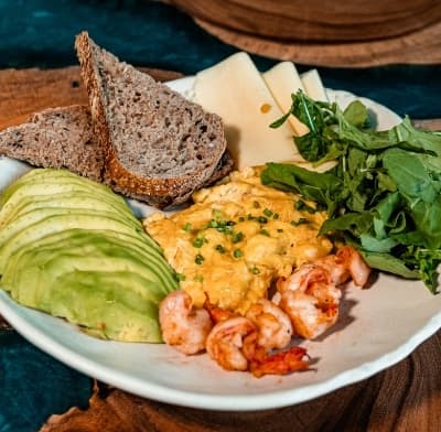 Atlantic breakfast — Fluffy scrambled eggs served with shrimp, avocado, emmental cheese, sourdough, and fresh rucola. A r