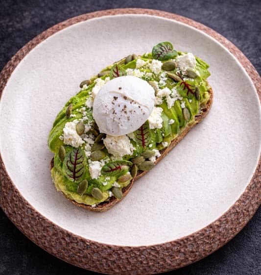 Avocado toast with poached egg — Homemade sourdough topped with guacamole, fresh avocado, and a perfectly poached egg. Finished with