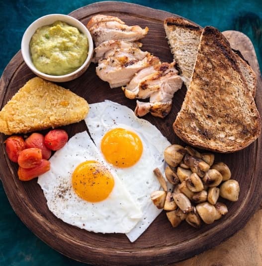Big protein breakfast — A hearty breakfast with eggs, grilled chicken thigh, mushrooms, guacamole, baked tomatoes, hashbrown