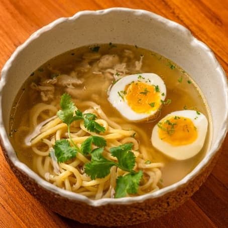 Chicken Soup — A comforting chicken broth with tender chicken, egg noodles, soft-boiled egg, and fresh parsley. Lig