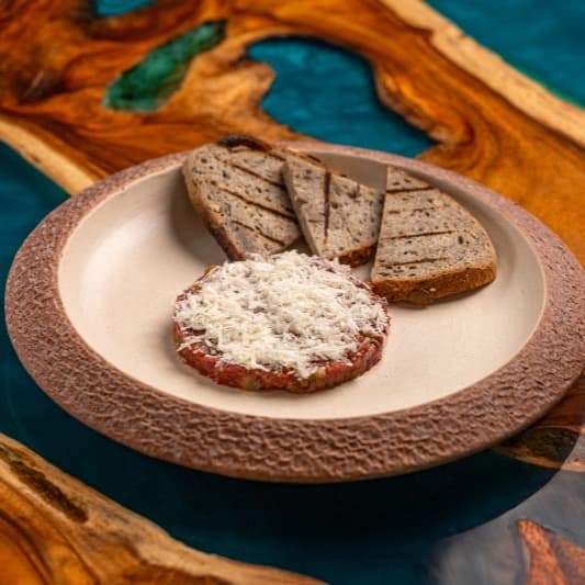 Marble beef tar-tar with sourdough — Classic French-style beef tar-tar with capers, shallot, pickles, mustard, and olive oil. Finished wi