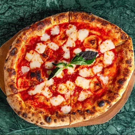 Margarita — Classic Neapolitan-style pizza with rich tomato sauce, melted mozzarella, and fresh basil. Simple, a