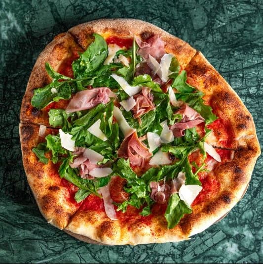 Prosciutto and rucola — Neapolitan pizza topped with tomato sauce, mozzarella, delicate prosciutto, fresh rucola, and parmes