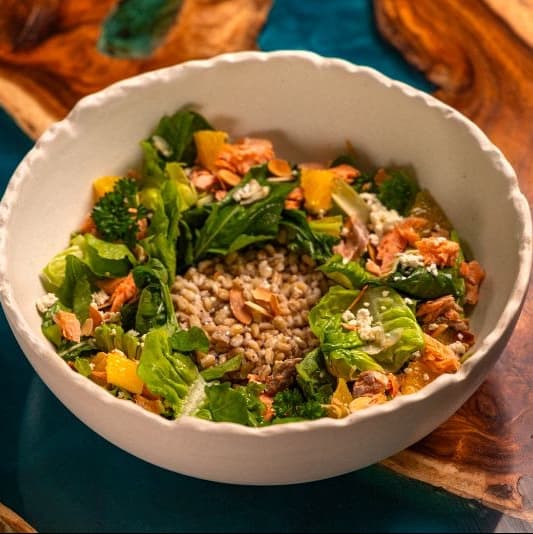Salmon and barleys — Mixed greens with baked salmon, barley, feta cheese, orange, almonds, and artichoke. A wholesome sal