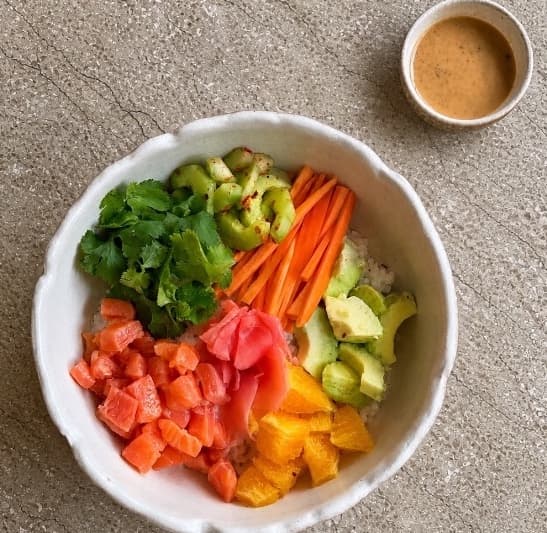 Salmon poke — A vibrant poke bowl with fresh salmon, Japanese rice, avocado, orange, cucumber, carrot, cilantro, a