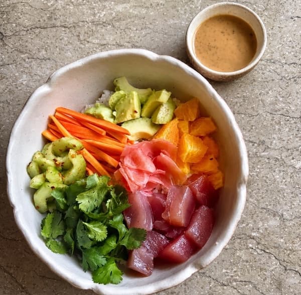 Tuna poke — Fresh tuna served over Japanese rice with avocado, orange, cucumber, carrot, cilantro, and marinated