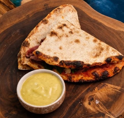 Vitello tonnato and roastbeef flatbread — Crispy pizza-dough flatbread filled with roast beef, parmesan, rucola, and capers. Served with cream