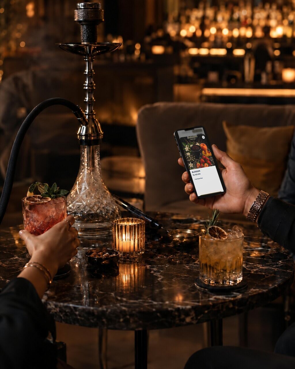A guest ordering from a phone at a lounge table with a hookah